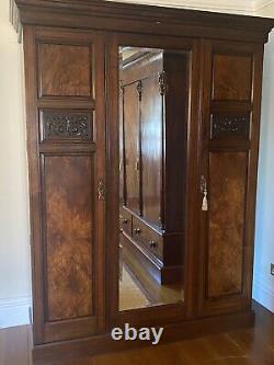 Grande armoire à trois portes avec miroir en noyer et acajou, comprenant des tiroirs profonds.