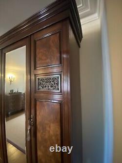 Grande armoire à trois portes avec miroir en noyer et acajou, comprenant des tiroirs profonds.